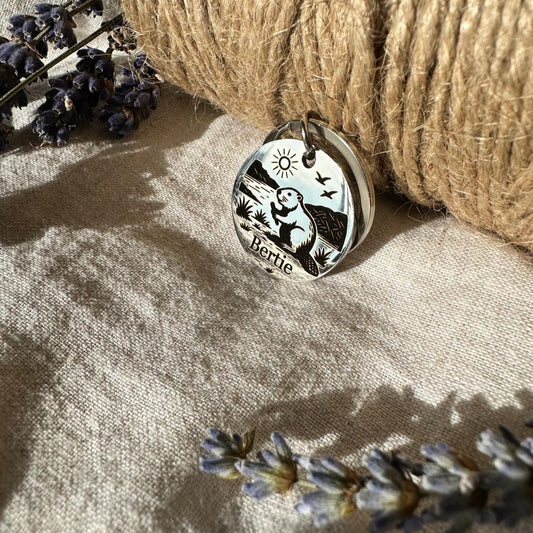 Silver pendant with beaver design on a textured surface with twine and lavender flowers.