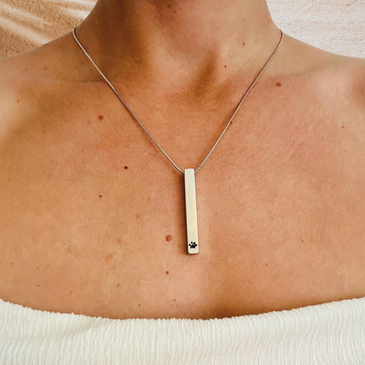 Necklace with a bar pendant on a person's neck against a neutral background