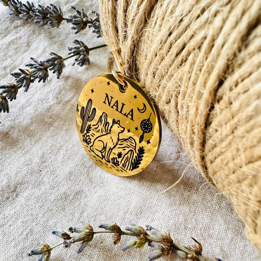 Gold pendant with 'NALA' engraving on a textured fabric background