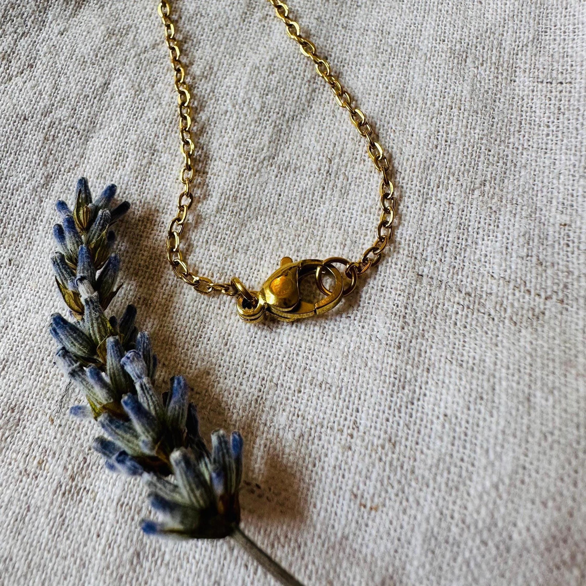 Gold necklace with a clasp on a textured beige background