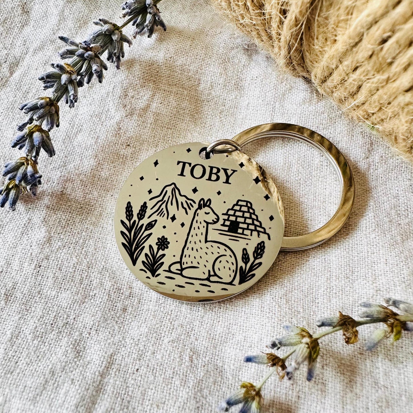 Dog tag with 'Toby' and llama illustration on a textured fabric background