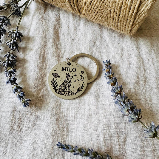 Round Dog tag with 'MILO' engraved, surrounded by lavender flowers on a textured fabric background