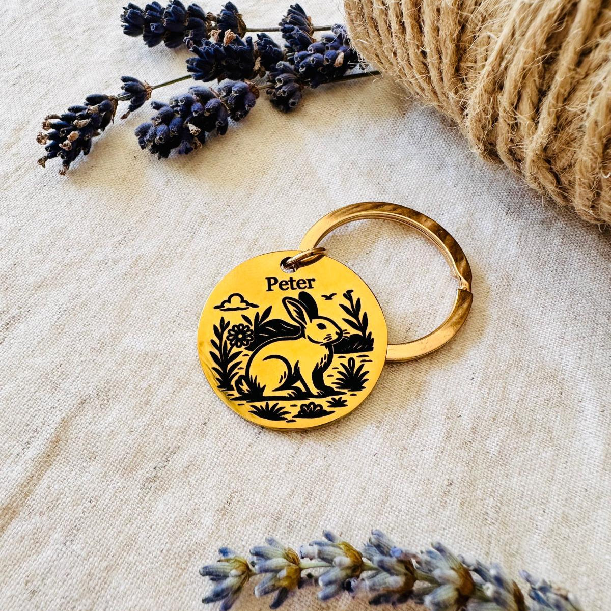 Personalised pet id tag with rabbit design on a textured surface with lavender and twine.