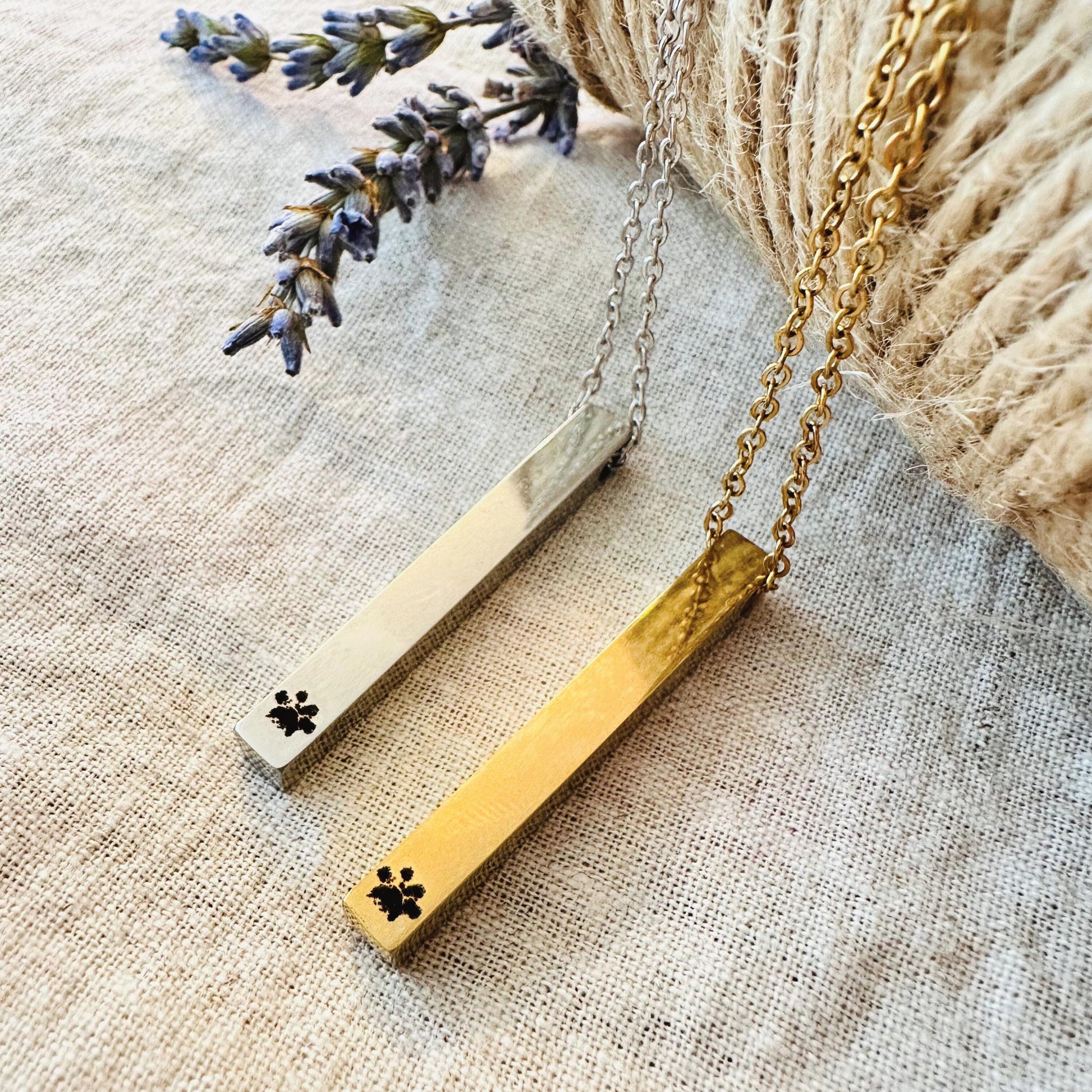 Gold necklace with paw print design on a textured fabric background