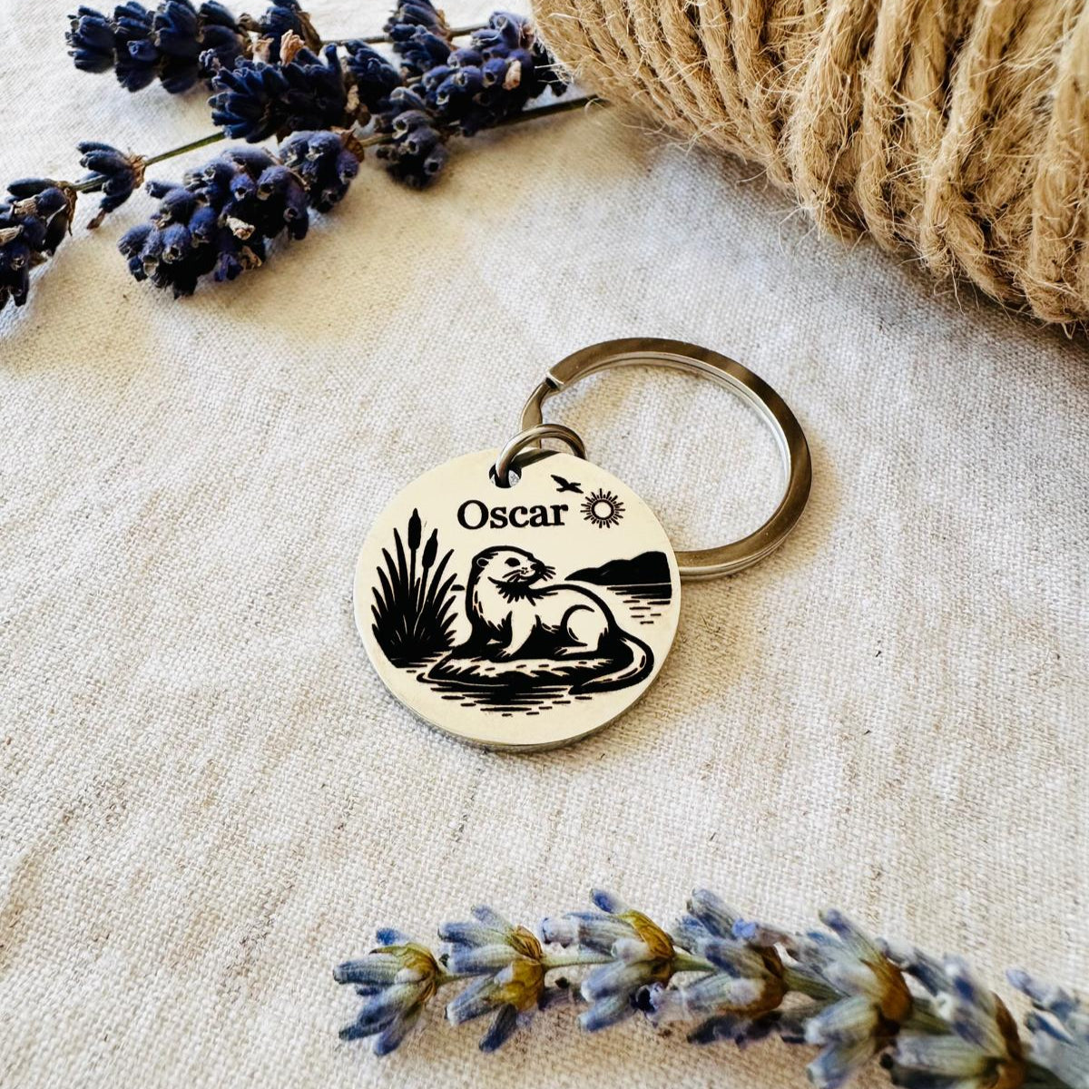 Pet id tag with 'Oscar' engraving on a textured surface with lavender and twine.