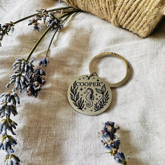 Keychain with 'Cooper' design on a textured fabric background with lavender flowers.