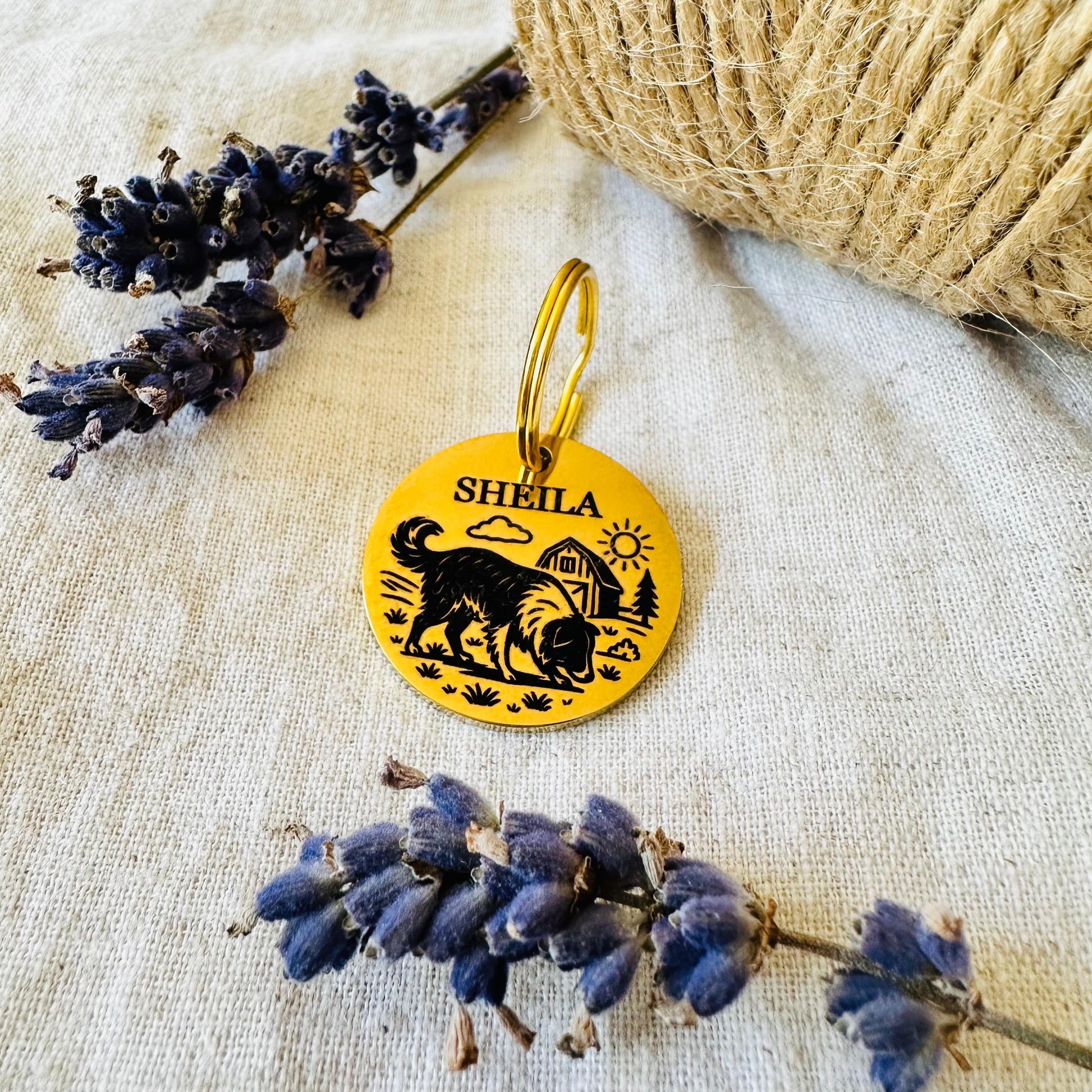 Gold pet tag with engraved sheepdog design, surrounded by lavender flowers on a textured fabric background