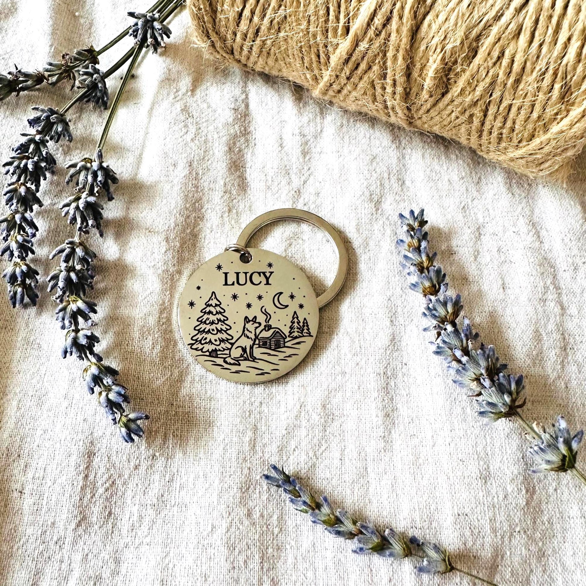 Dog tag with 'Lucy' engraving on a textured surface with lavender and yarn.